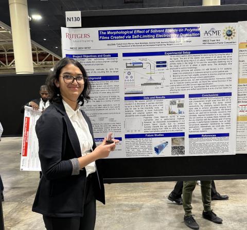 Isha smiling in front of her poster.